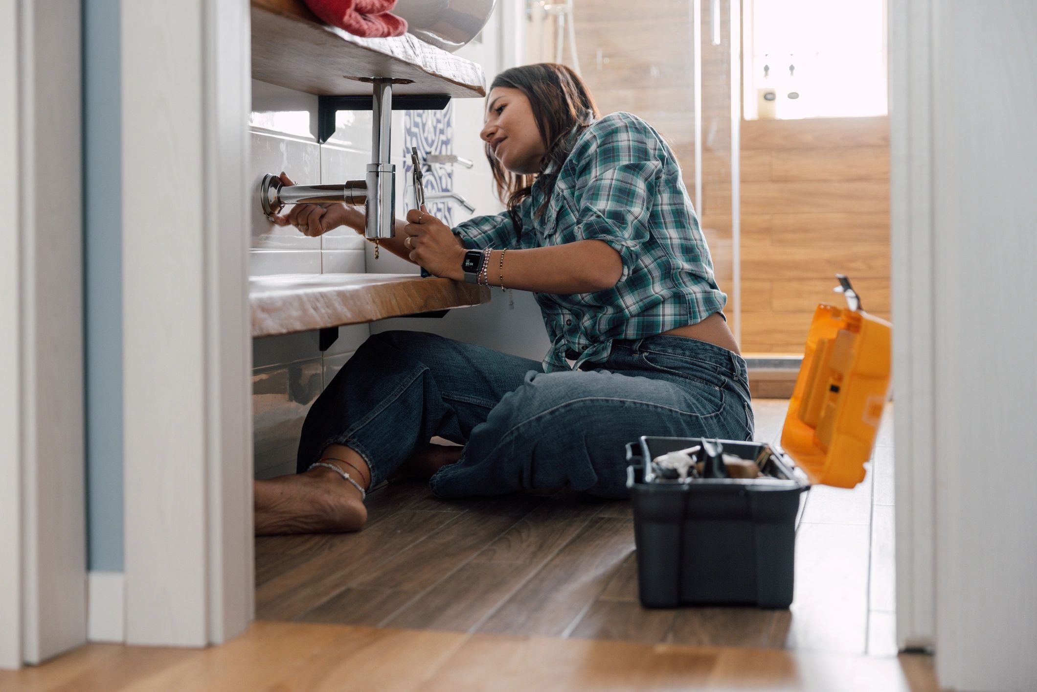 Technician working beneath a kitchen cabinet on plumbing